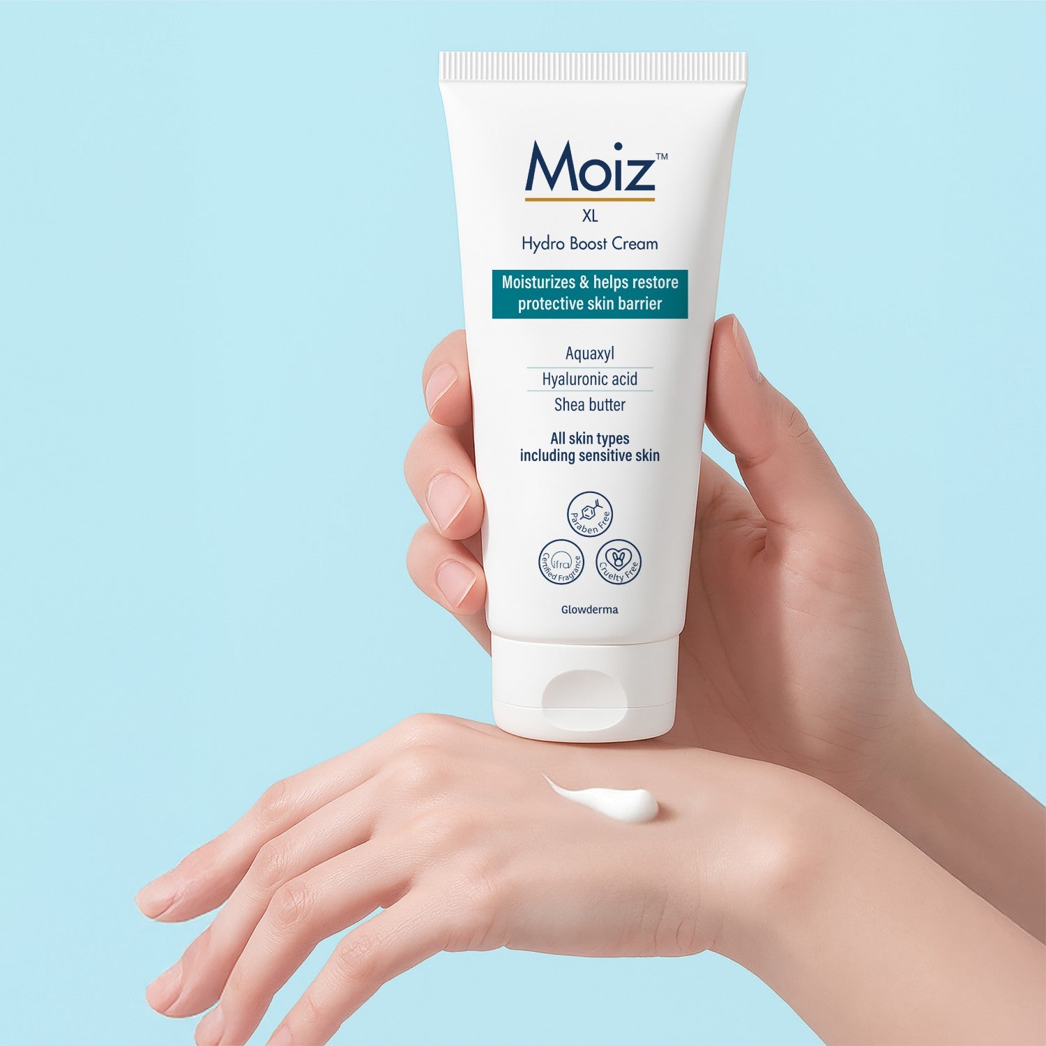 Hand holding a Moiz XL Hydro Boost Cream tube with a light blue background