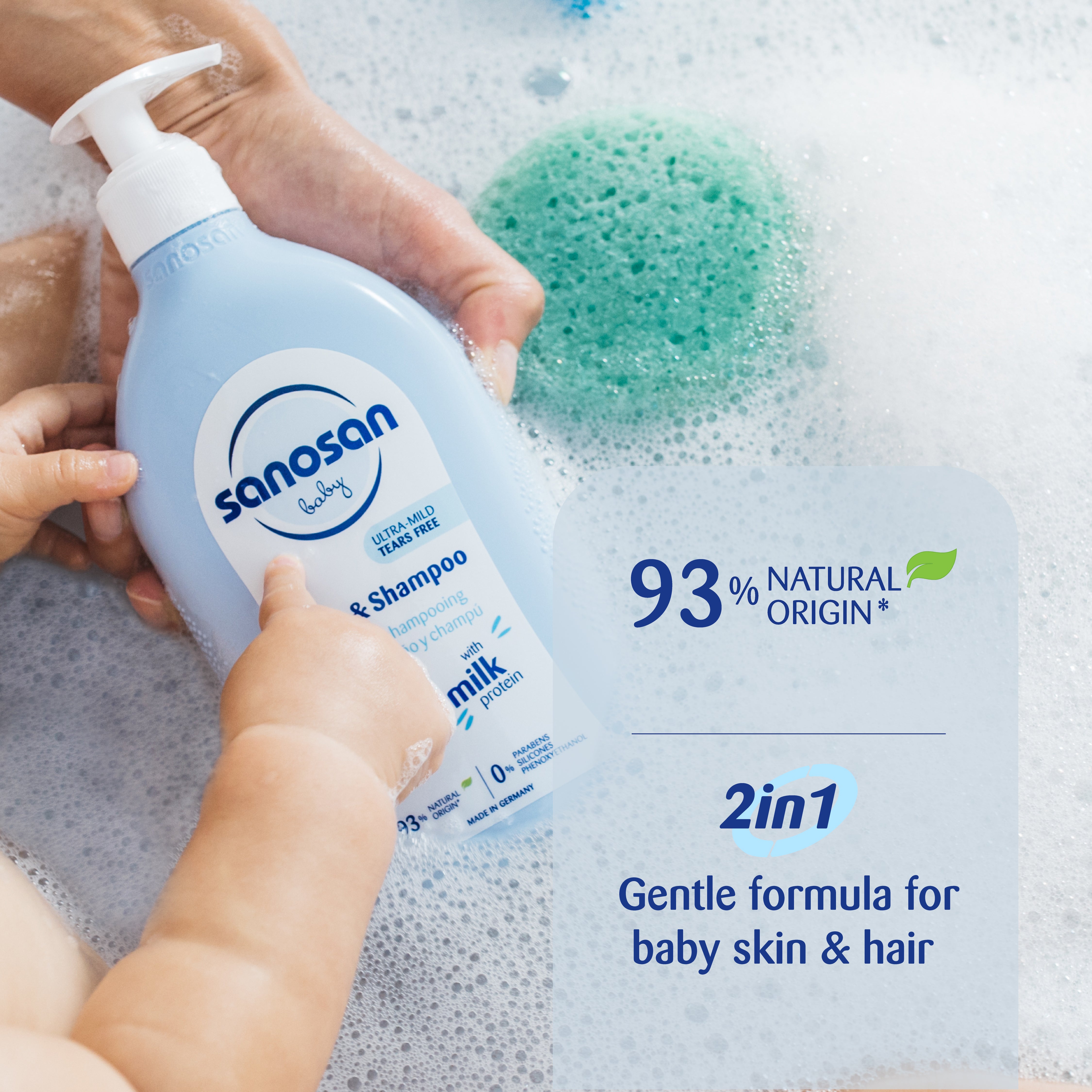 Sanasan baby shampoo and soap bottle with hands holding it, surrounded by bubbles and a green sponge.