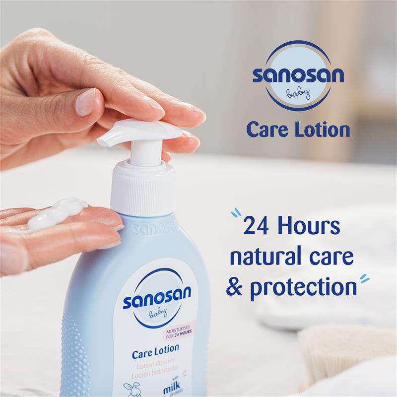 Sanosan baby care lotion bottle with a hand holding it, against a blurred background.